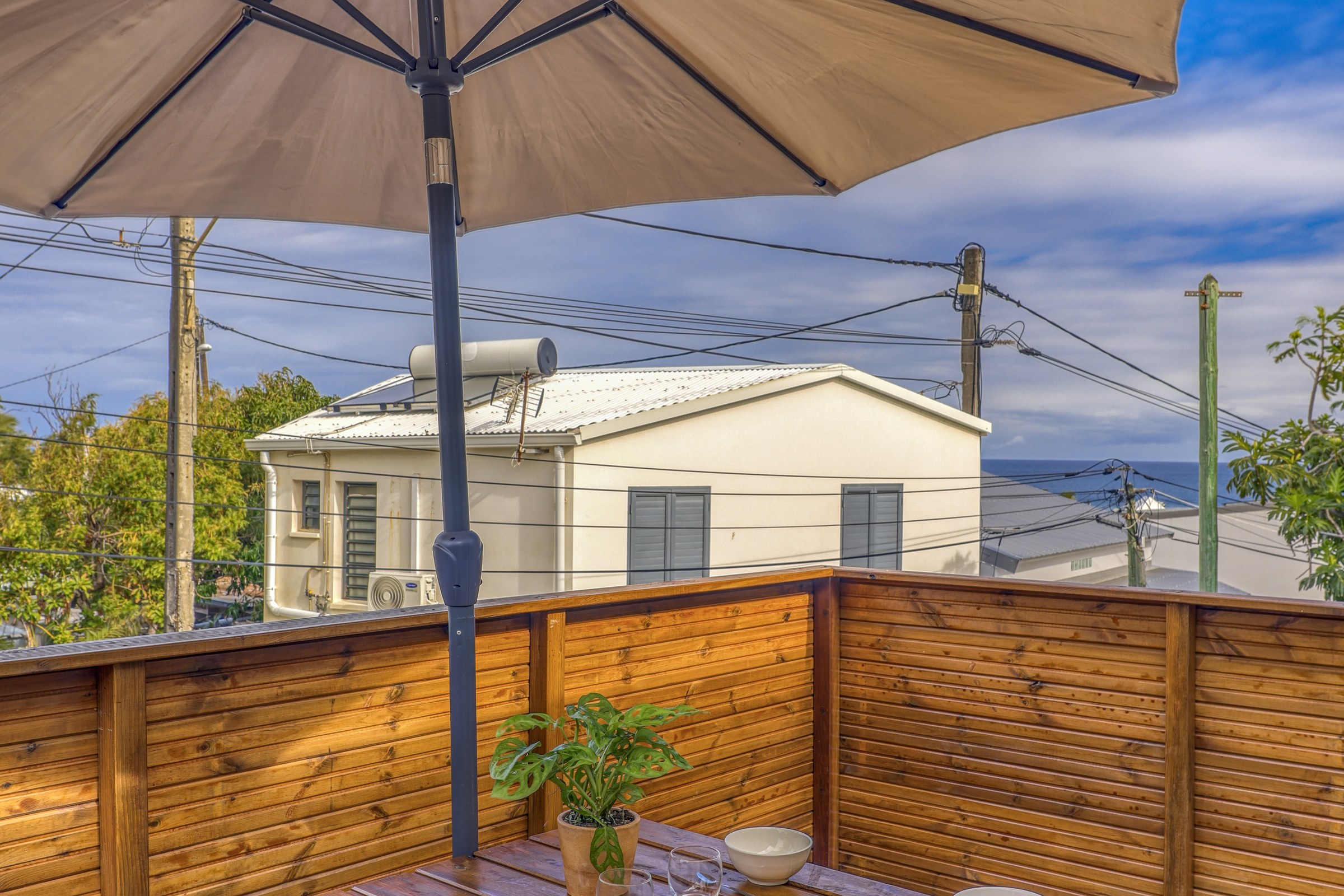 Terrasse en bois du grand T3 avec table, bancs et grand parasol