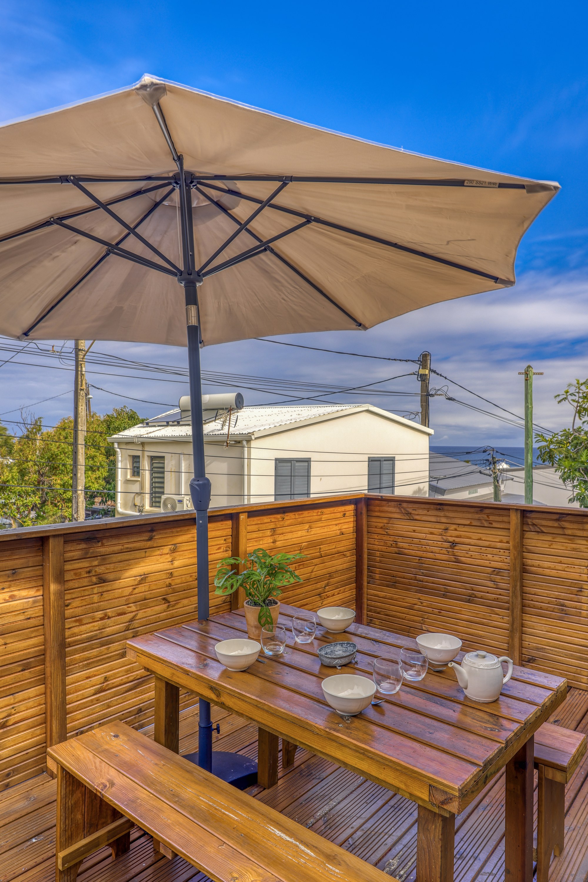 Terrasse en bois du grand T3 avec table, bancs et grand parasol