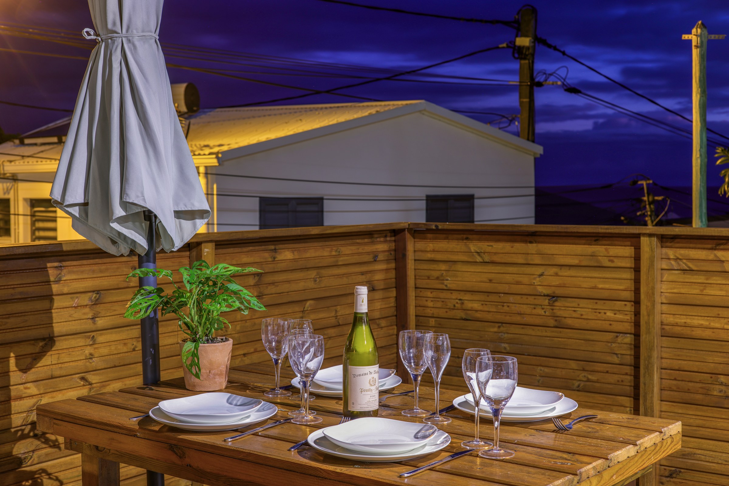 Terrasse du grand T3 éclairée de nuit, table dressée pour le dîner