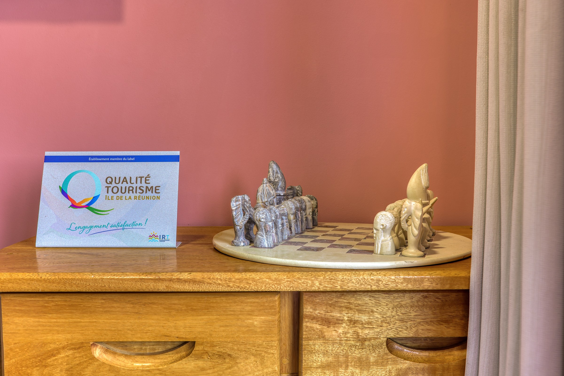 Jeu d'échecs artisanal posé sur une commode en bois, dans le salon du grand T3