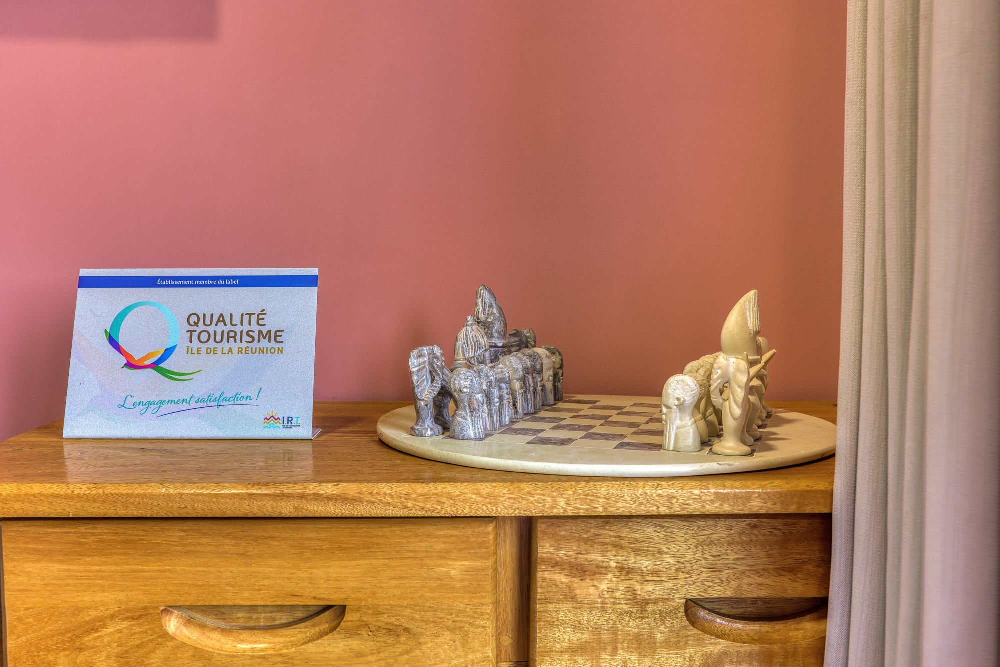 Jeu d'échecs artisanal posé sur une commode en bois, dans le salon du grand T3