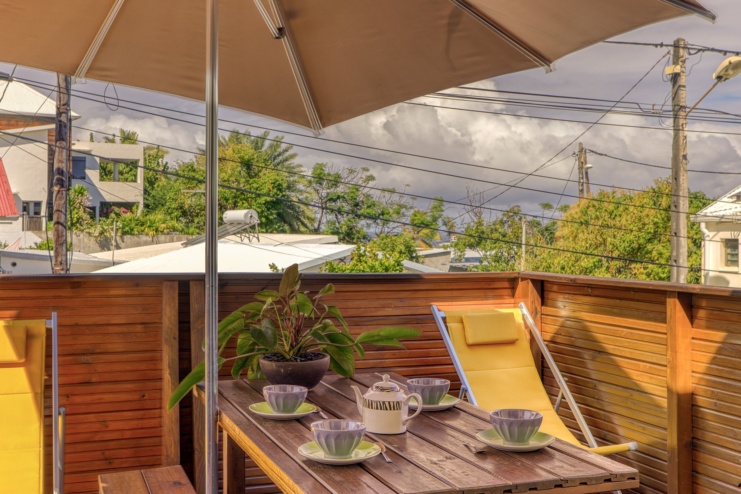 Terrasse en bois du T3 avec parasol, chaises longues et table à déjeuner