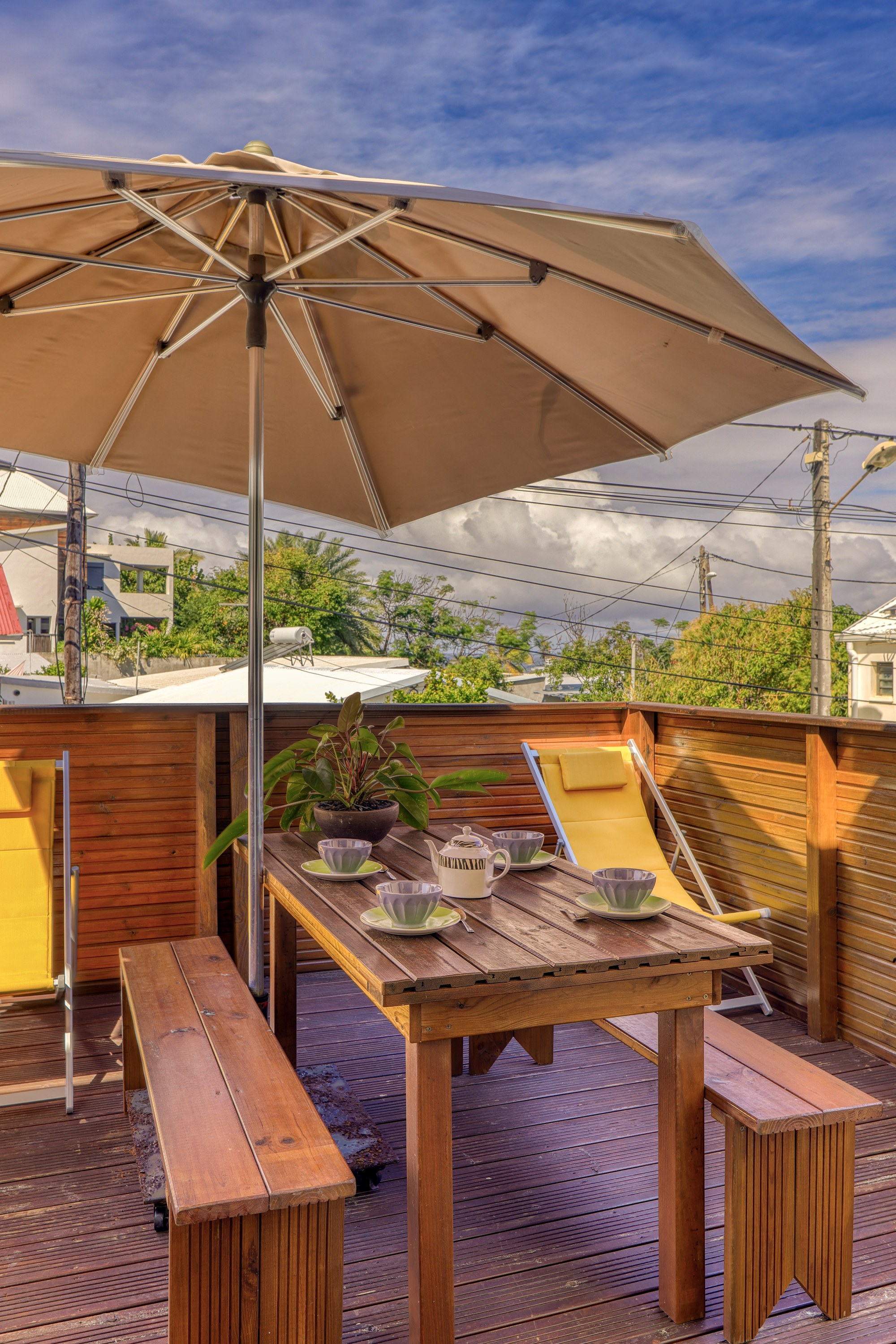 Terrasse en bois du T3 avec parasol, chaises longues et table à déjeuner