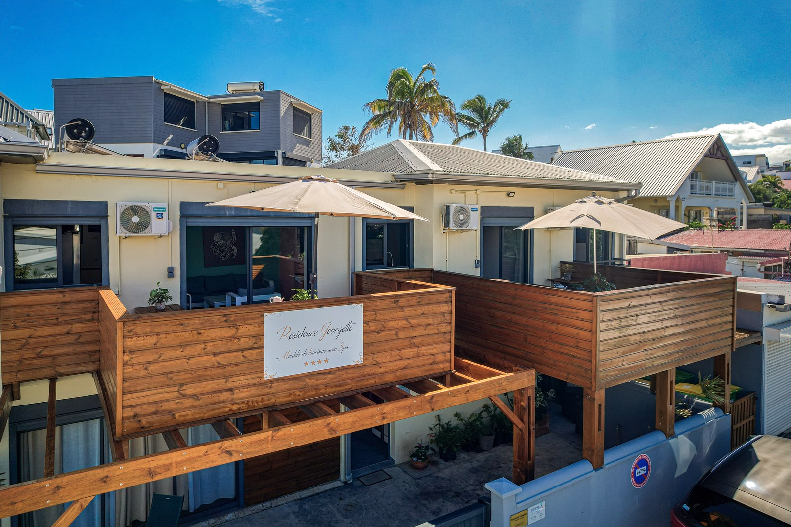 Façade de la Résidence Georgette, ses balcons en bois et ses parasols, à Terre-Sainte