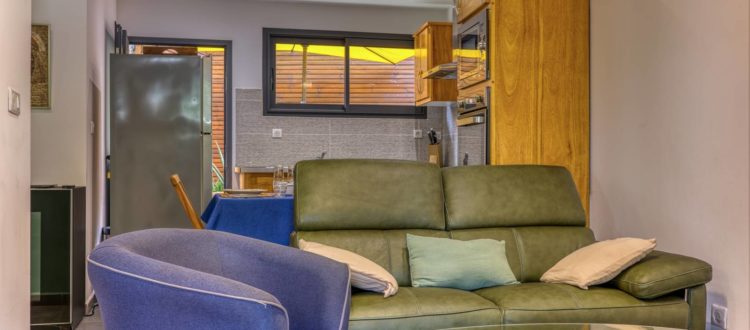 Salon design avec TV et canapé face à la cuisine – Appartement T2 Terre-Sainte