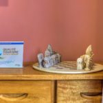 Jeu d’échecs artisanal sur commode en bois sous un mur rose