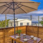 Terrasse en bois équipée d’une table et bancs sous un grand parasol