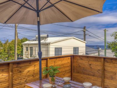 Terrasse en bois équipée d’une table et bancs sous un grand parasol