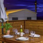 Terrasse bois éclairée avec table dressée pour le dîner
