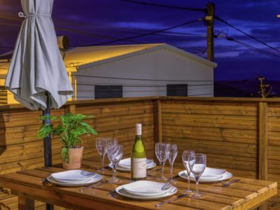 Terrasse bois éclairée avec table dressée pour le dîner