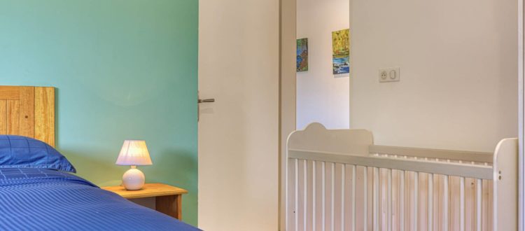 Chambre du T3 aménagée avec un lit bébé à la Résidence Georgette