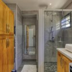 Salle de bain avec douche à l'italienne, meuble en bois et miroir mural