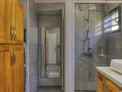 Salle de bain avec douche à l'italienne, meuble en bois et miroir mural