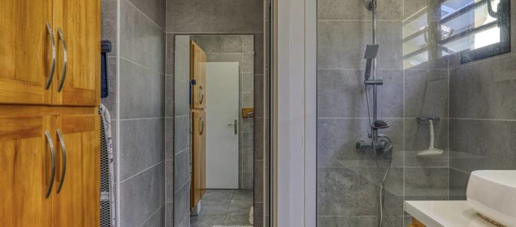 Salle de bain avec douche à l'italienne, meuble en bois et miroir mural