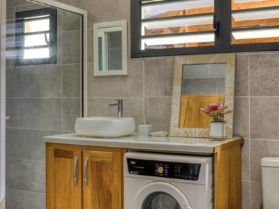 Salle de bain avec meuble vasque, lave-linge et fenêtre à persiennes