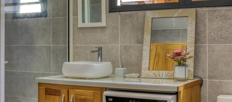 Salle de bain avec meuble vasque, lave-linge et fenêtre à persiennes