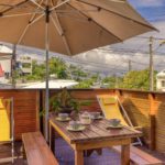 Terrasse en bois avec parasol, chaises longues et table à déjeuner