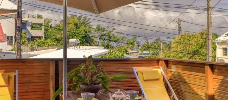 Terrasse en bois avec parasol, chaises longues et table à déjeuner