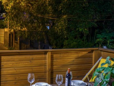 Terrasse éclairée de nuit avec table dressée et végétation en fond